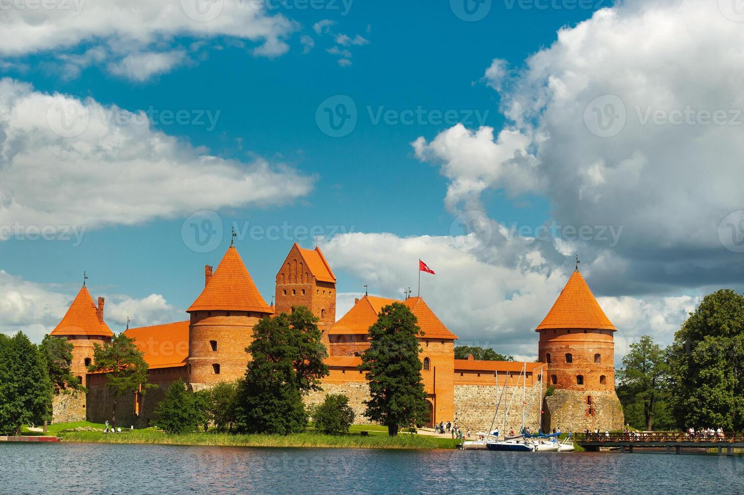 Lithuania. View on Trakai castle across lake and white yacht under sail photo