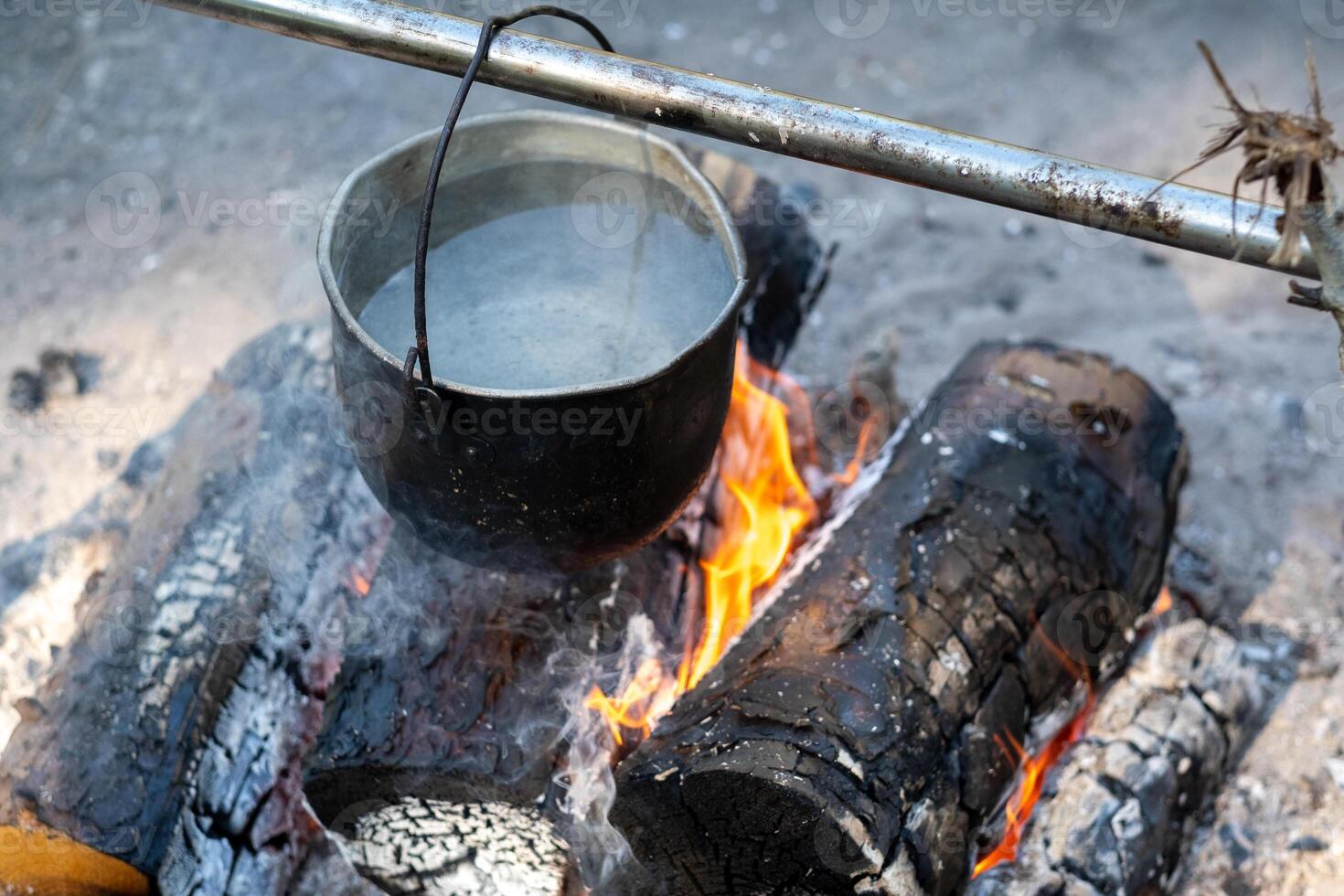 throw the ingredients into the soup which is cooked over a fire in a pot photo
