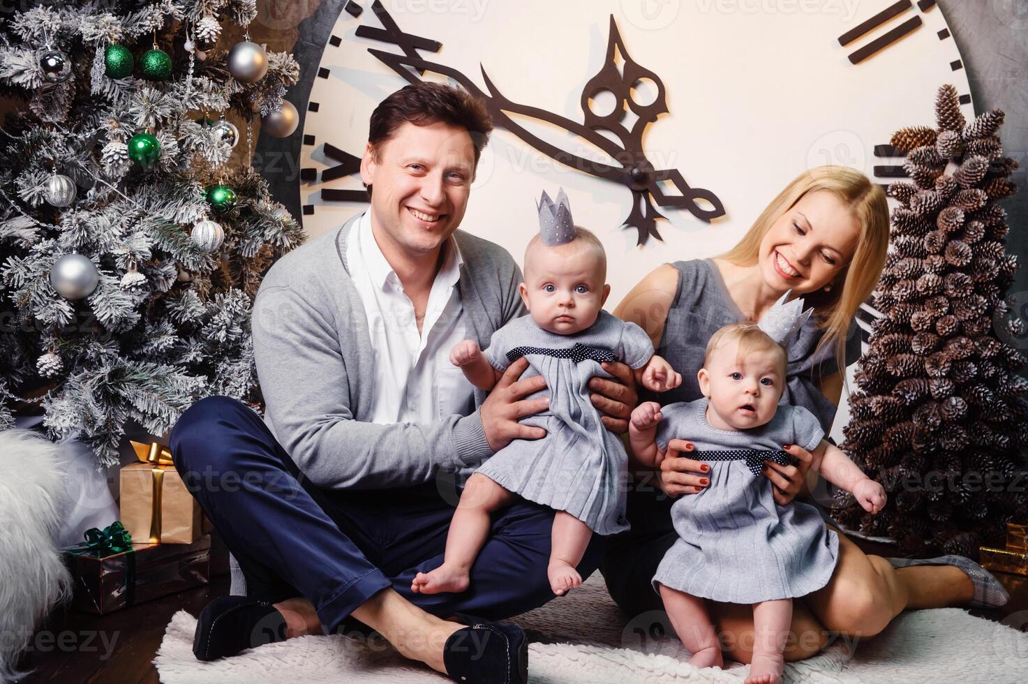 A happy big family with twin children in the New Year's interior of the house against the background of a large clock photo