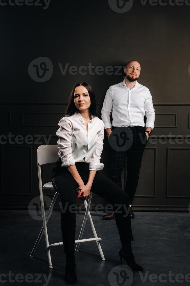 A man and a woman in white shirts on a black background.A couple in love in the studio interior photo