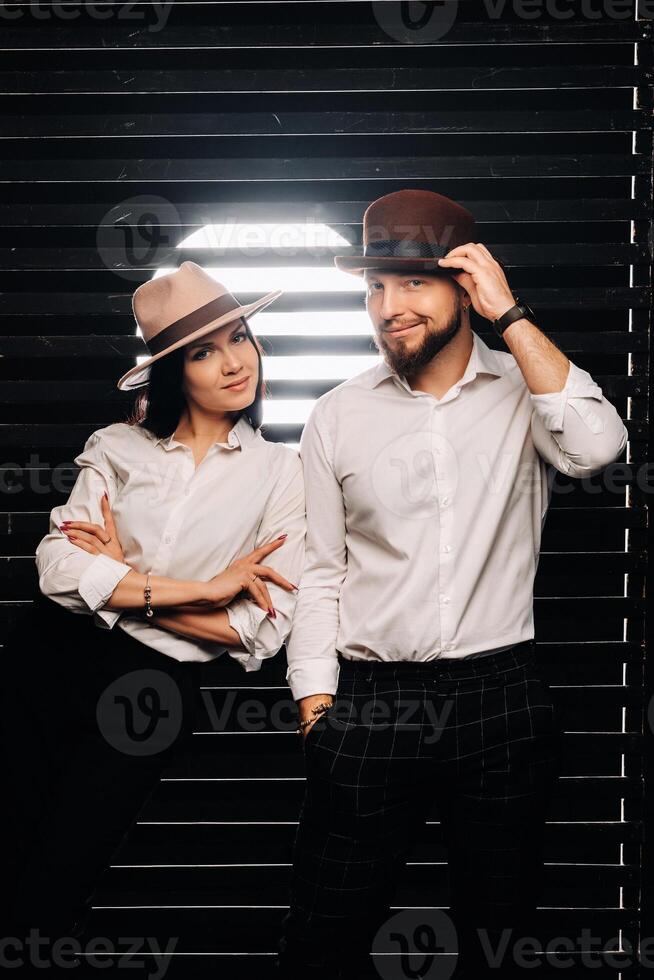 A man and a woman in white shirts and hats on a black background.A couple in love poses in the interior of the studio photo