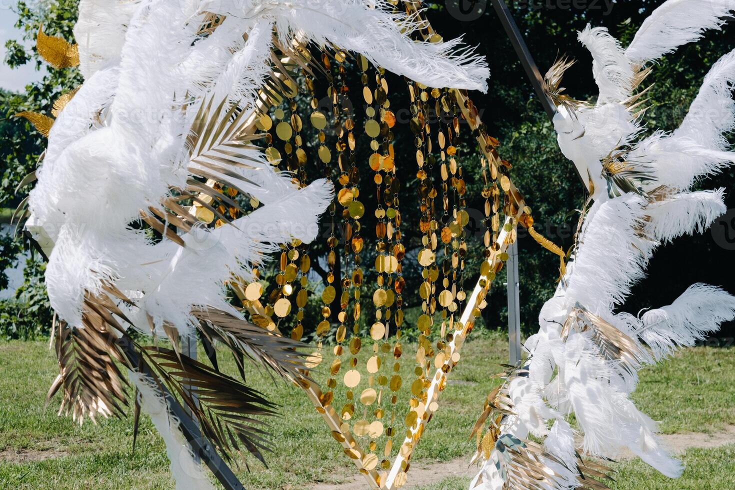 Decorated wedding arch in nature.Wedding ceremony with an arch decorated with feathers in retro style photo