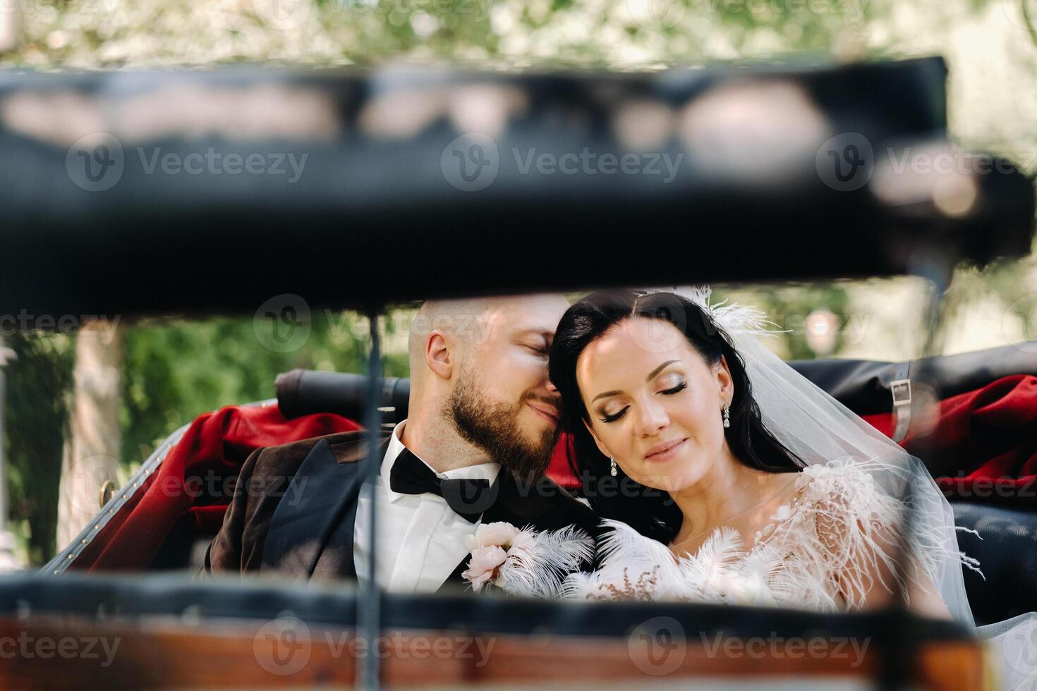 The bride and groom with a bouquet are sitting in a carriage in nature in retro style photo