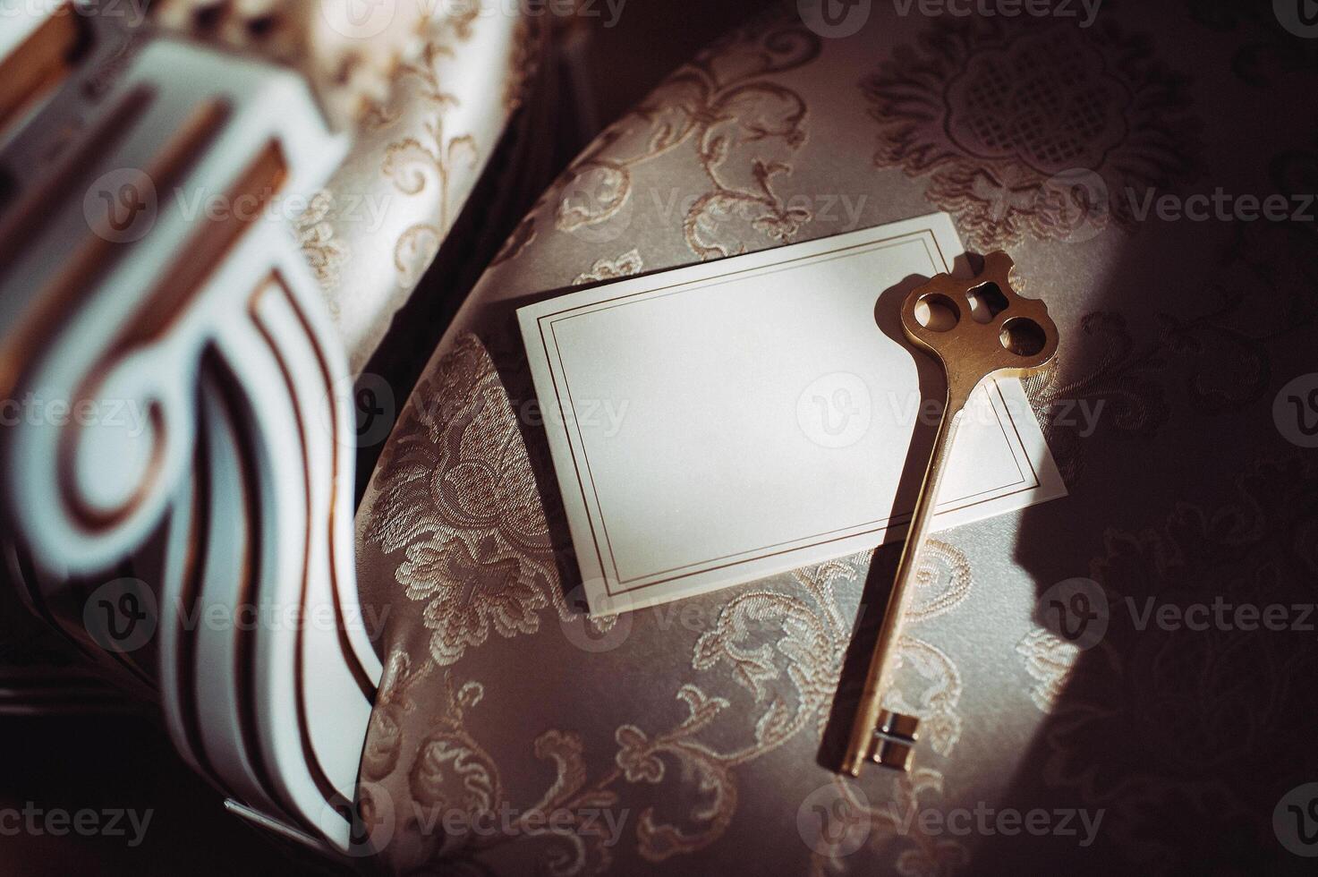 a postcard and an old key on the background of an old natural chair. Empty space for a postcard with your text. The view from the top of an old key and a blank card photo