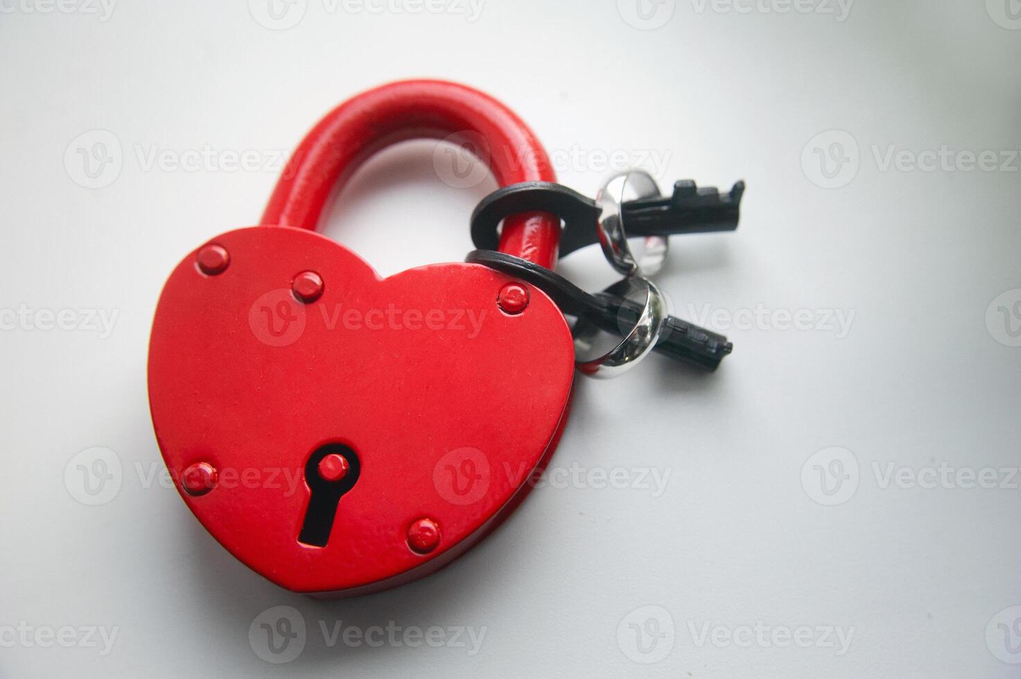 Red lock with keys and two wedding rings on a white background photo