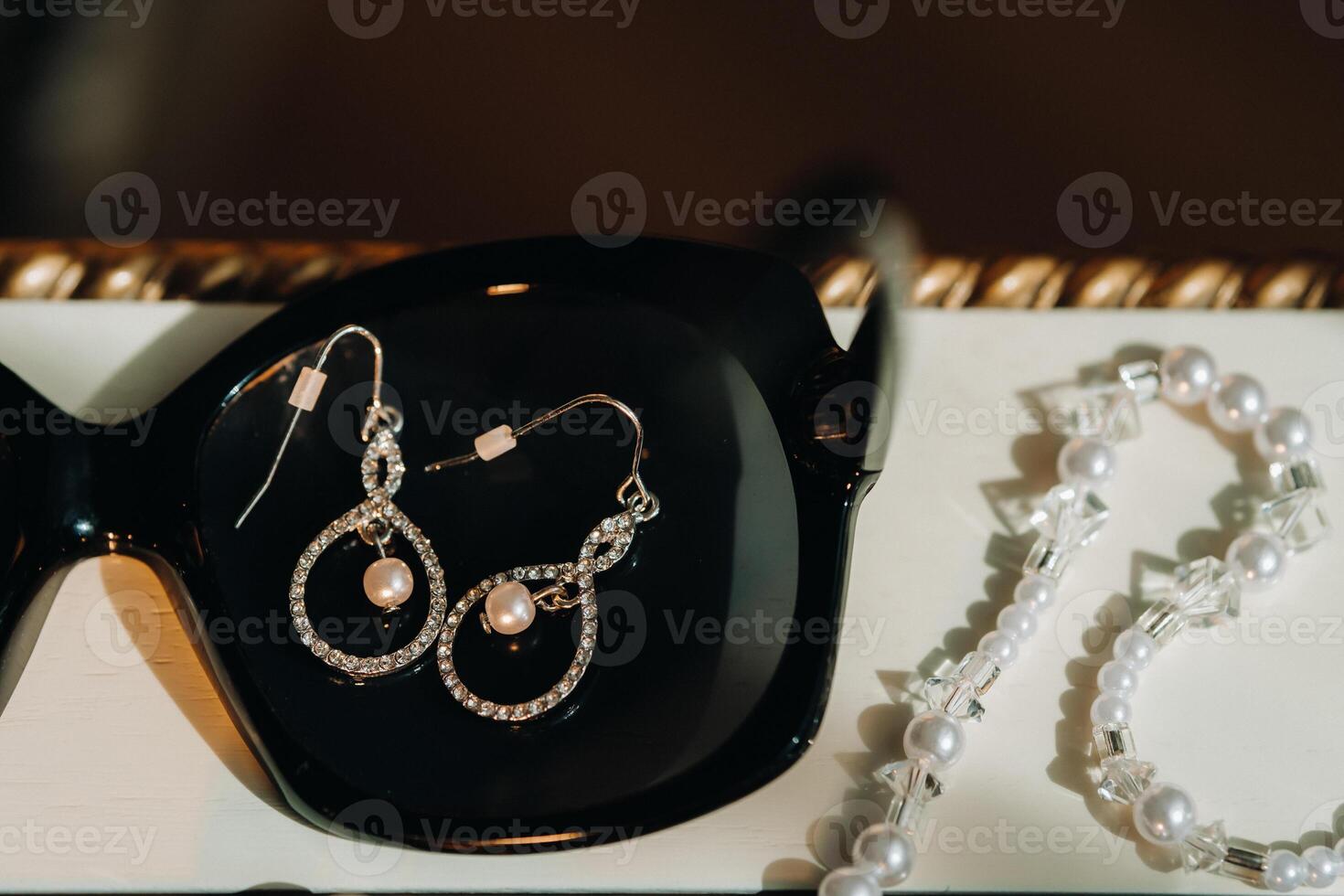 Accessories for the bride. Earrings on a black background. White wedding earrings. Space for text and ads. photo