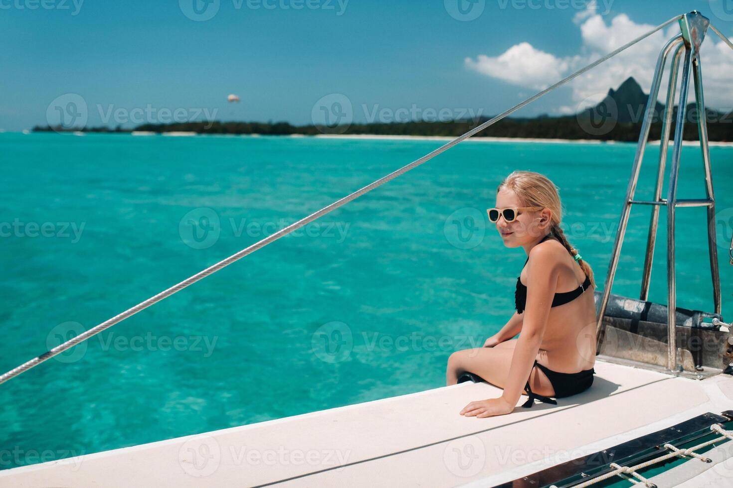 a little girl sits on a catamaran in the Indian ocean. portrait of a girl on a boat in the coral reef of the island of Mauritius photo