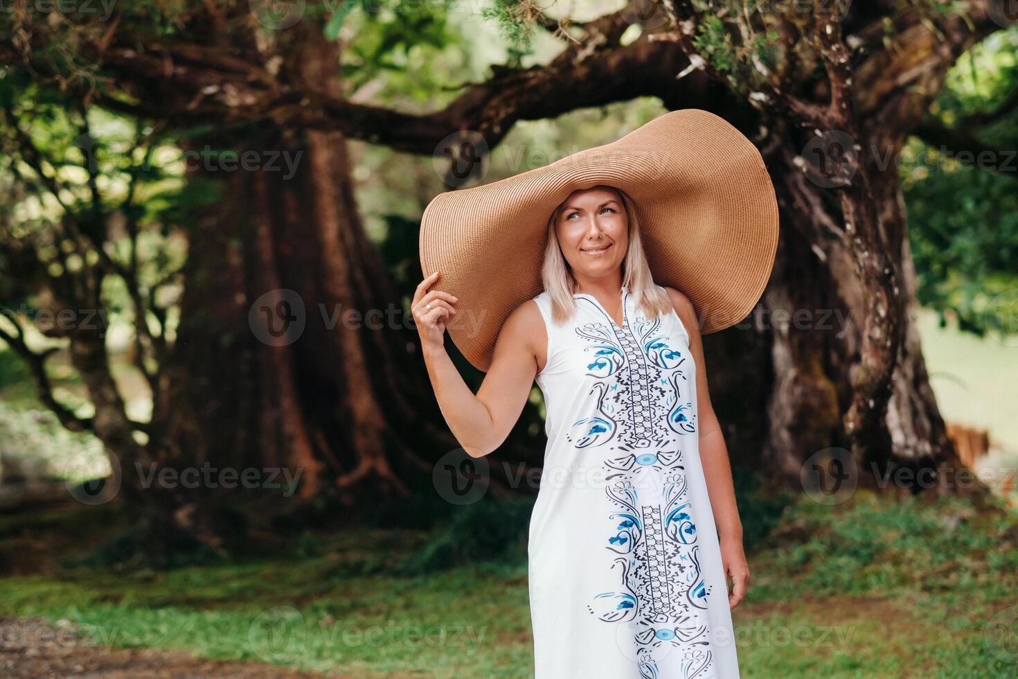 A woman in a large hat and long dress poses on the island of Mauritius. beautiful girl resting on the island of Mauritius photo