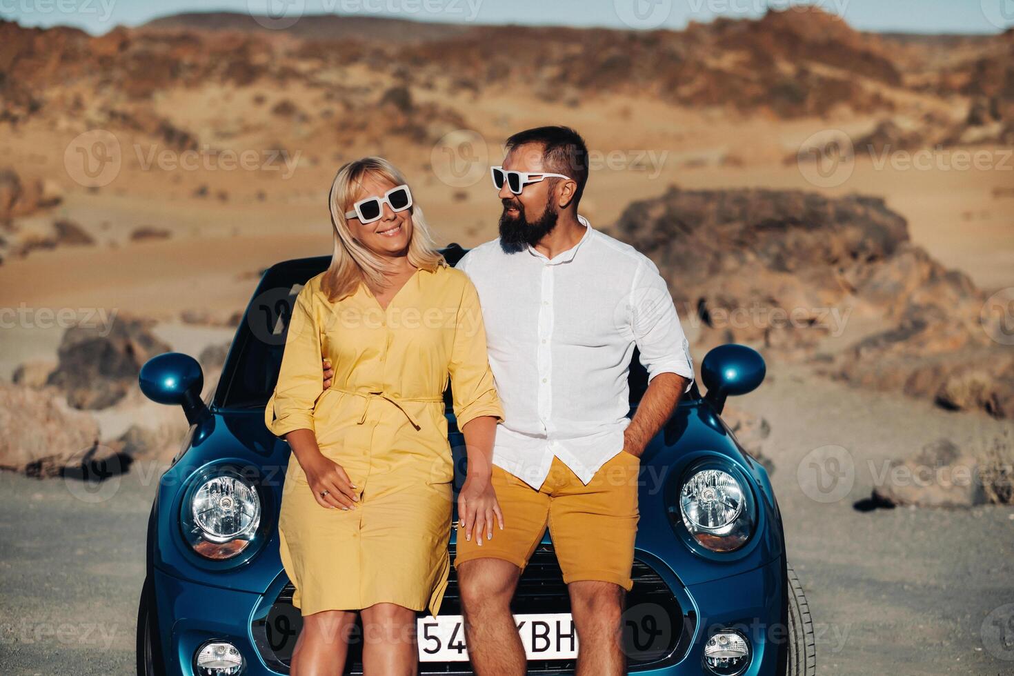 a woman and a man wearing glasses in a convertible car on a trip to the island of Tenerife. The crater of the Teide volcano, Canary Islands,Spain photo