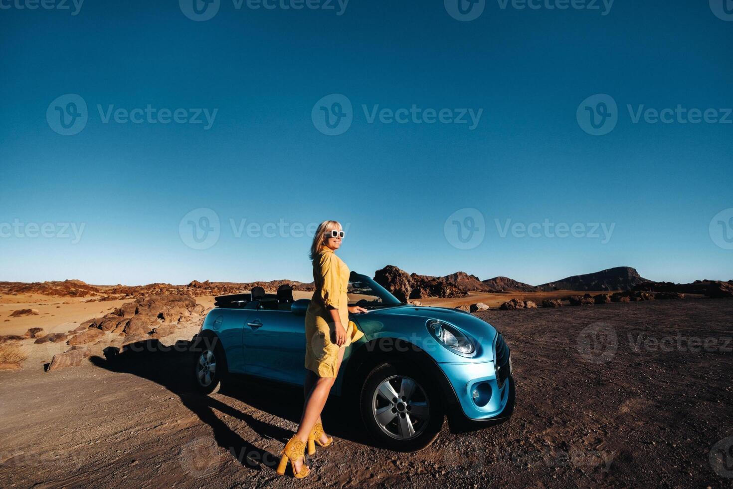 Woman enjoying road trip, standing with map near convertible car on the roadside in the volcanic mountain forest on Tenerife island, Spain. photo