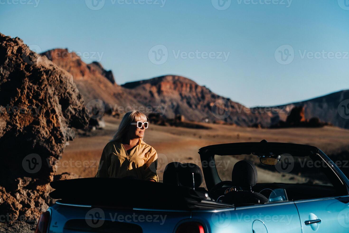 Woman enjoying road trip, standing with map near convertible car on the roadside in the volcanic mountain forest on Tenerife island, Spain. photo