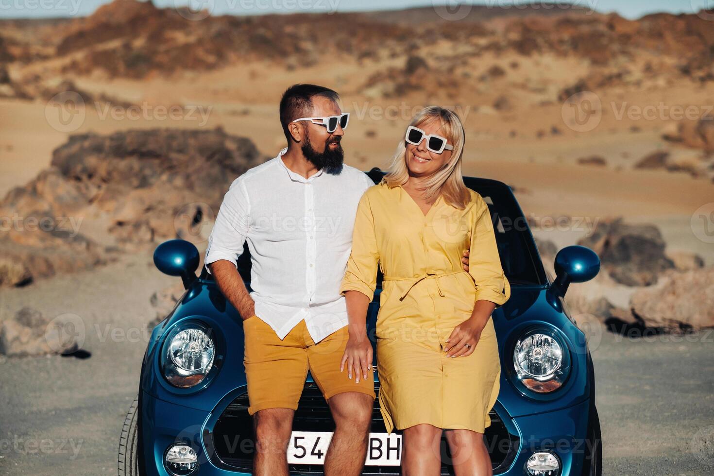 a woman and a man wearing glasses in a convertible car on a trip to the island of Tenerife. The crater of the Teide volcano, Canary Islands,Spain photo