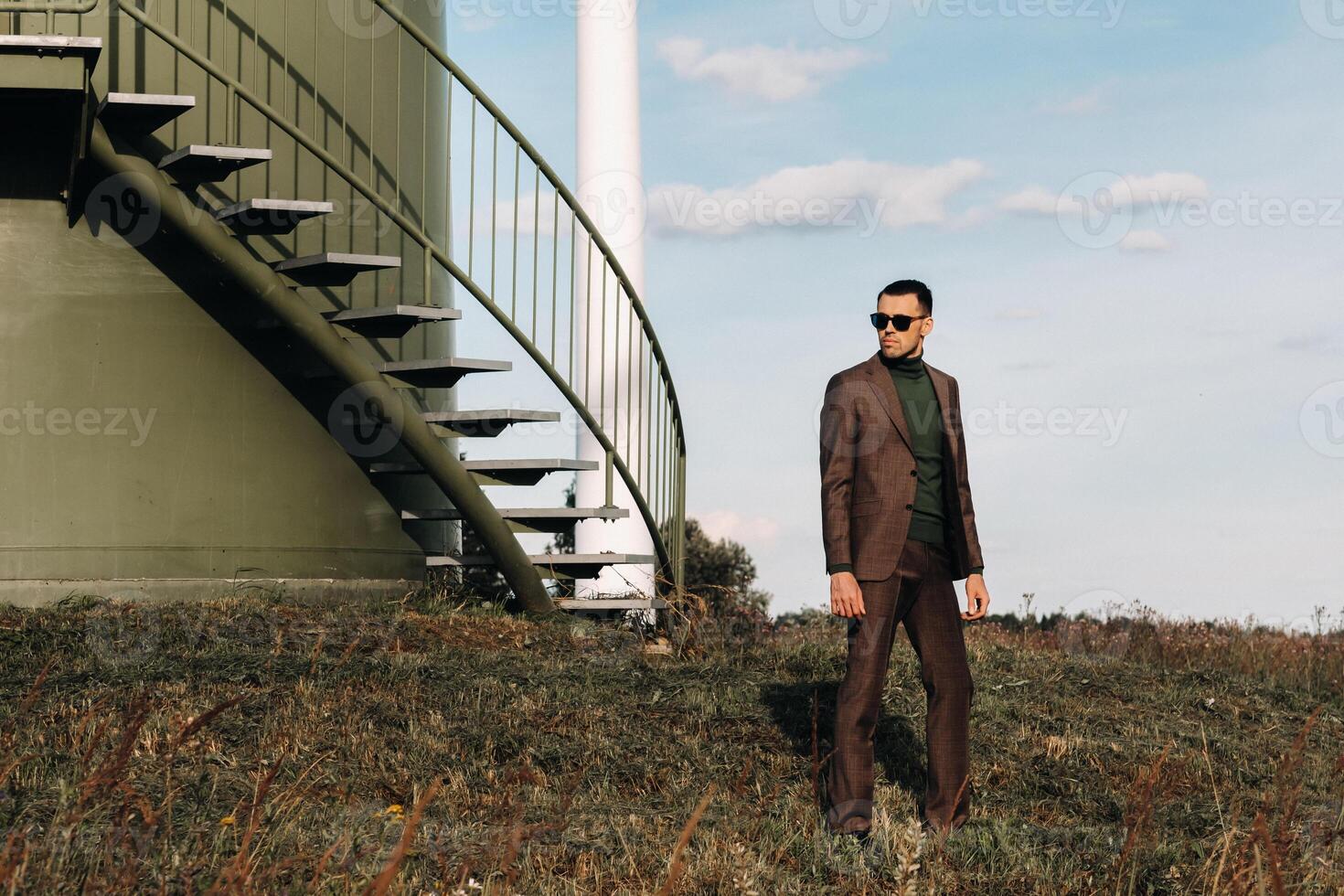 A man in a business suit and green Golf shirt stands next to a green windmill.Businessman near the windmills.Modern concept of the future. photo