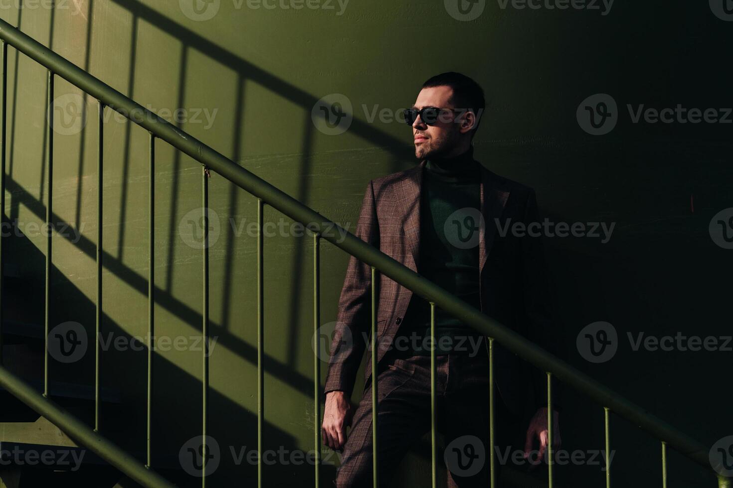 A man in a business suit and green Golf shirt stands next to a green windmill.Businessman near the windmills.Modern concept of the future. photo