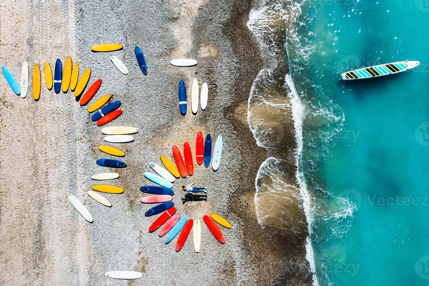 a beautiful couple is lying on the beach of France next to surfboards, shooting from a quadcopter, a lot of surfboards are unusually lying on the beach photo