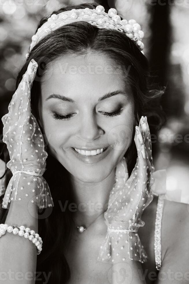 An elegant bride in a white dress, gloves with a bouquet on a waterfall in the Park, enjoying nature.Model in a wedding dress and gloves in the forest.Belarus photo