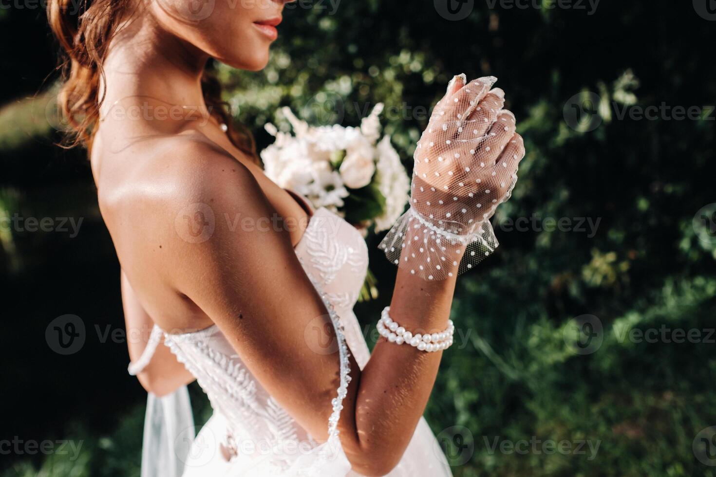 portrait of an elegant bride in a white dress with a bouquet in nature in a nature Park.Model in a wedding dress and gloves and with a bouquet .Belarus photo