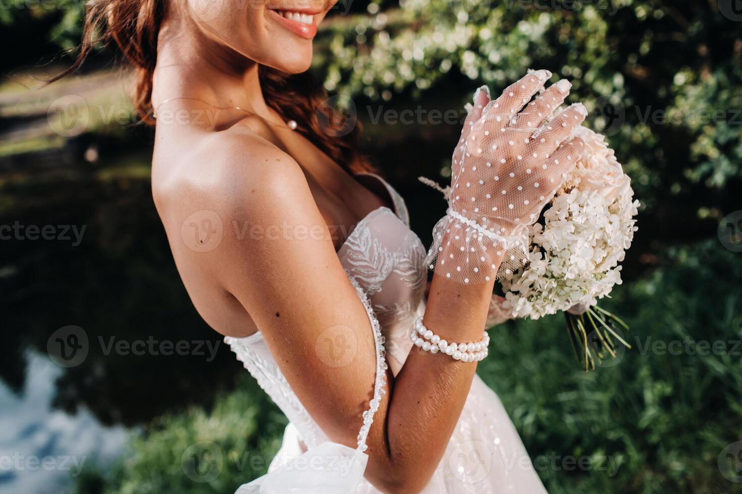 portrait of an elegant bride in a white dress with a bouquet in nature in a nature Park.Model in a wedding dress and gloves and with a bouquet .Belarus photo