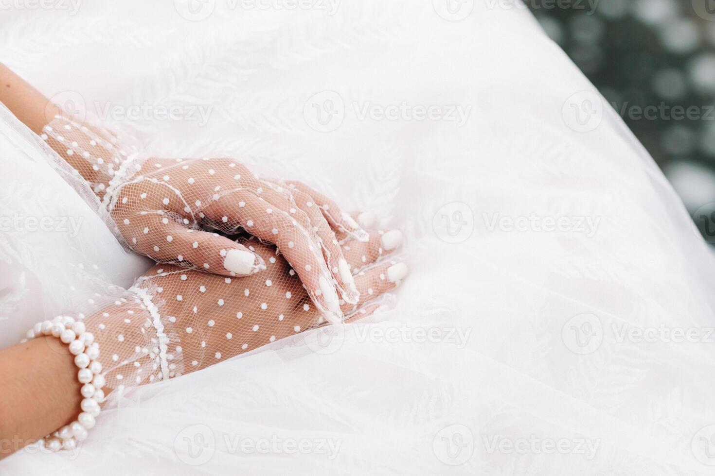 Close-up of the bride's hands in white transparent gloves near a waterfall in the Park.A model in a wedding dress and mesh gloves in a nature Park.Belarus photo