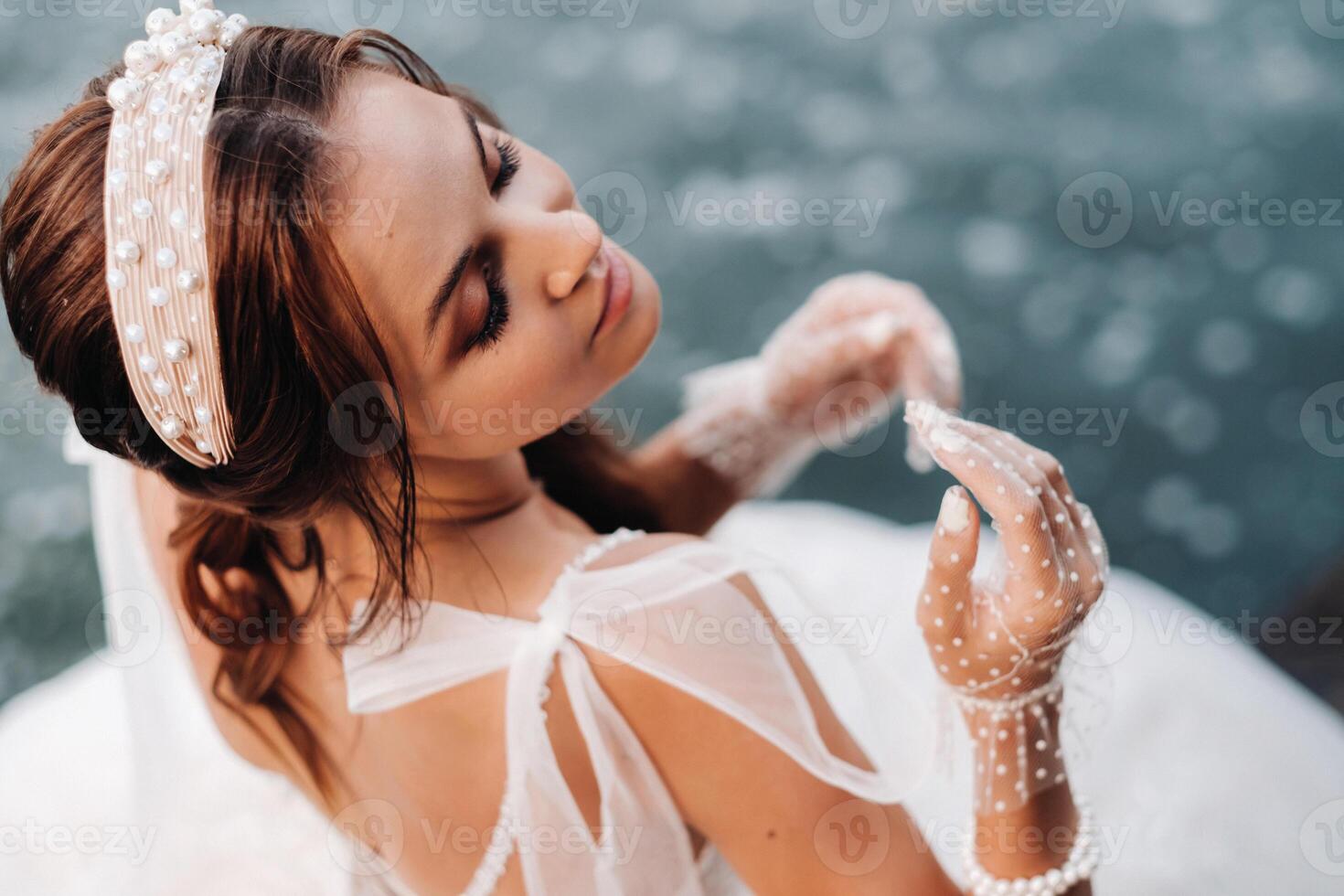 An elegant bride in a white dress, gloves and bare feet is sitting near a waterfall in the Park enjoying nature.A model in a wedding dress and gloves at a nature Park.Belarus. black and white photo