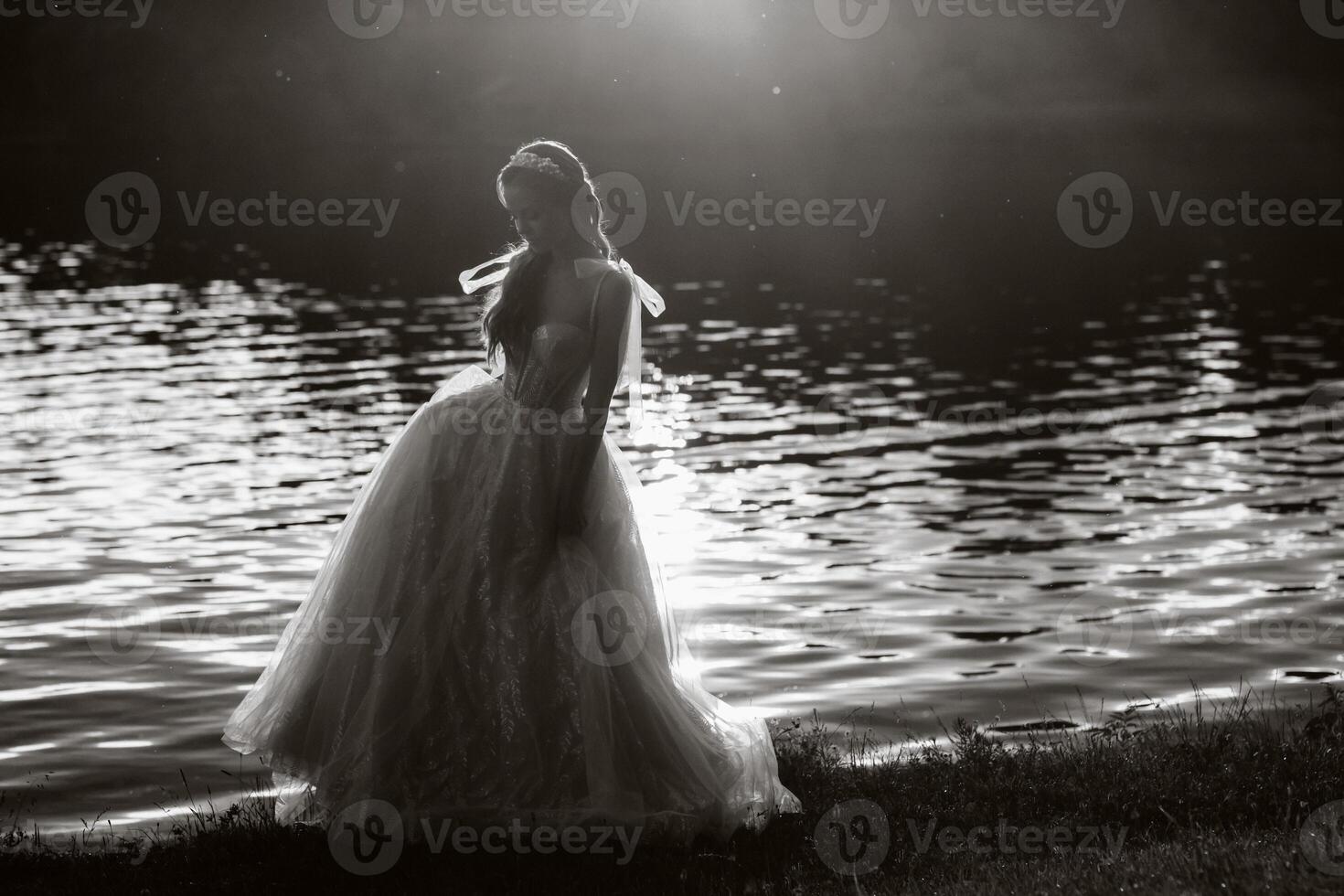 An elegant bride in a white dress enjoys nature at sunset.Model in a wedding dress in nature in the Park.Belarus. black and white photo