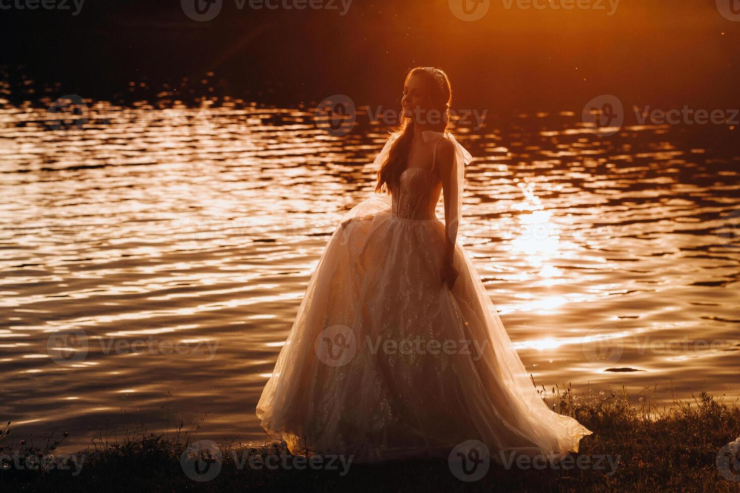 An elegant bride in a white dress enjoys nature at sunset.Model in a wedding dress in nature in the Park.Belarus photo