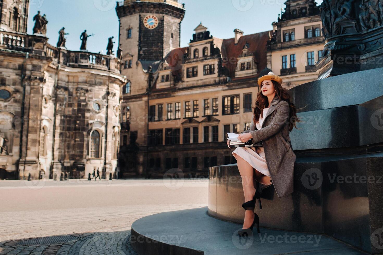 a stylish young beautiful girl is sitting and typing in the Old town of Dresden.Germany. photo