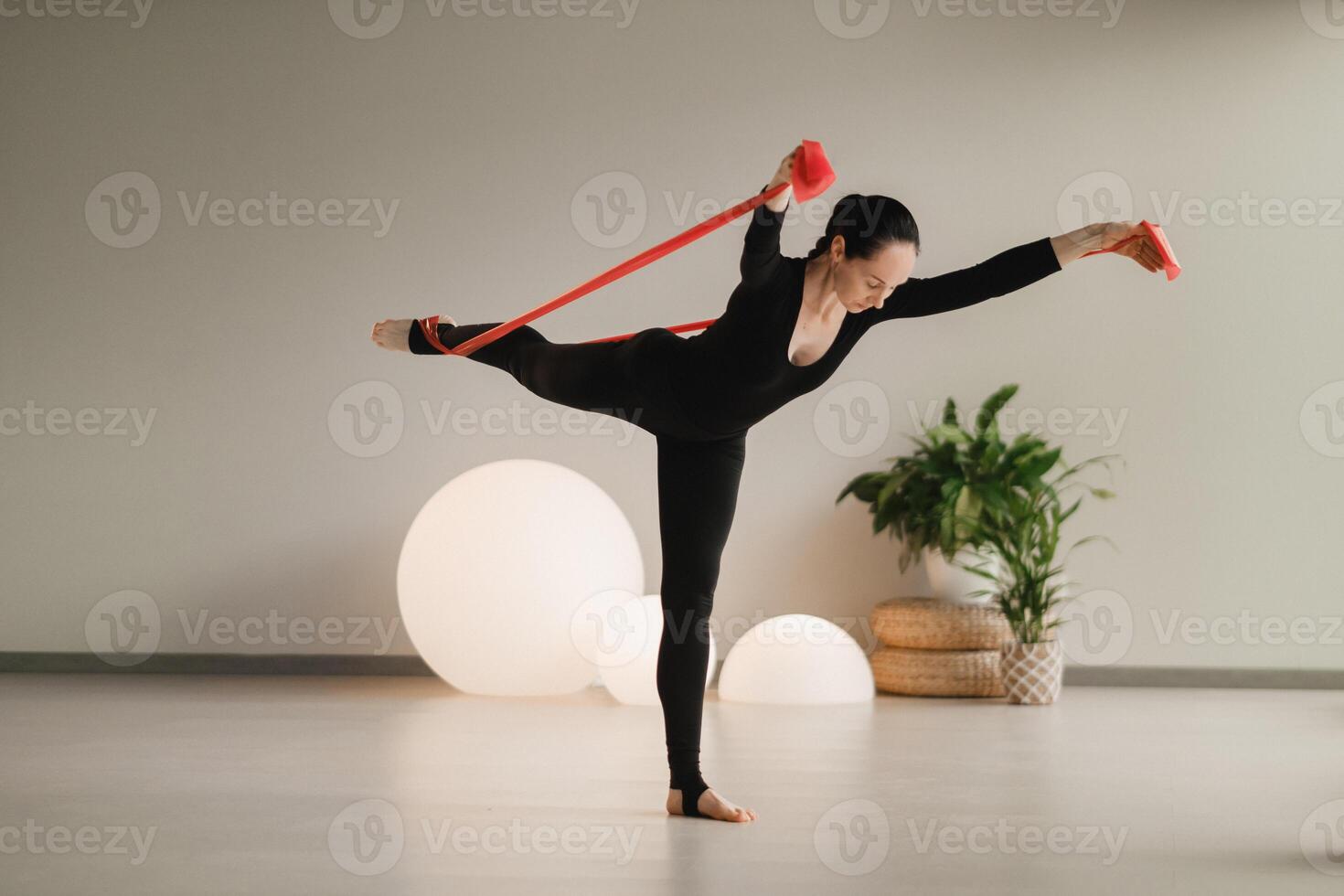 Girl in black doing fitness with red ribbons indoors photo