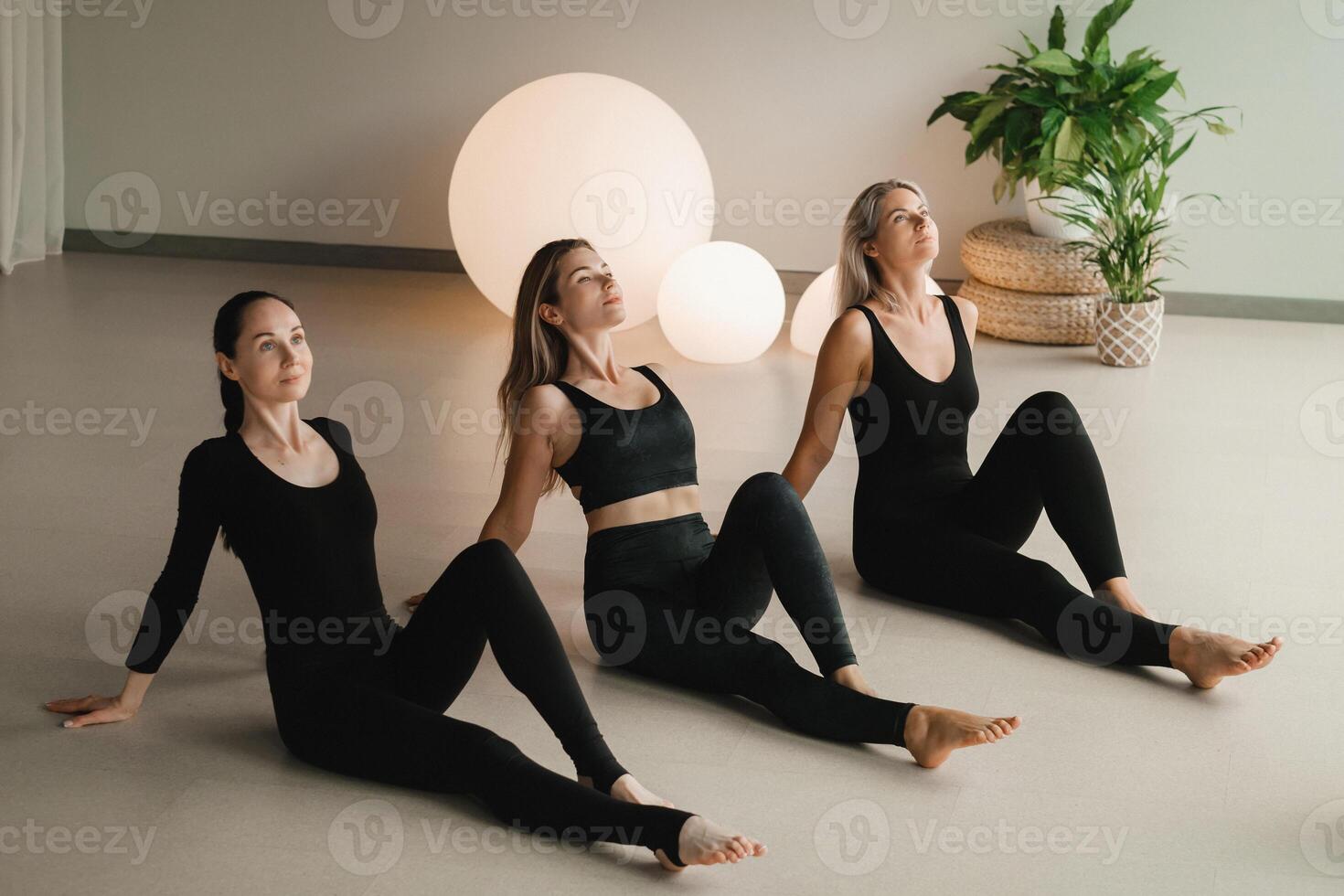 A group of girls in black doing yoga poses indoors. Women are engaged in fitness photo