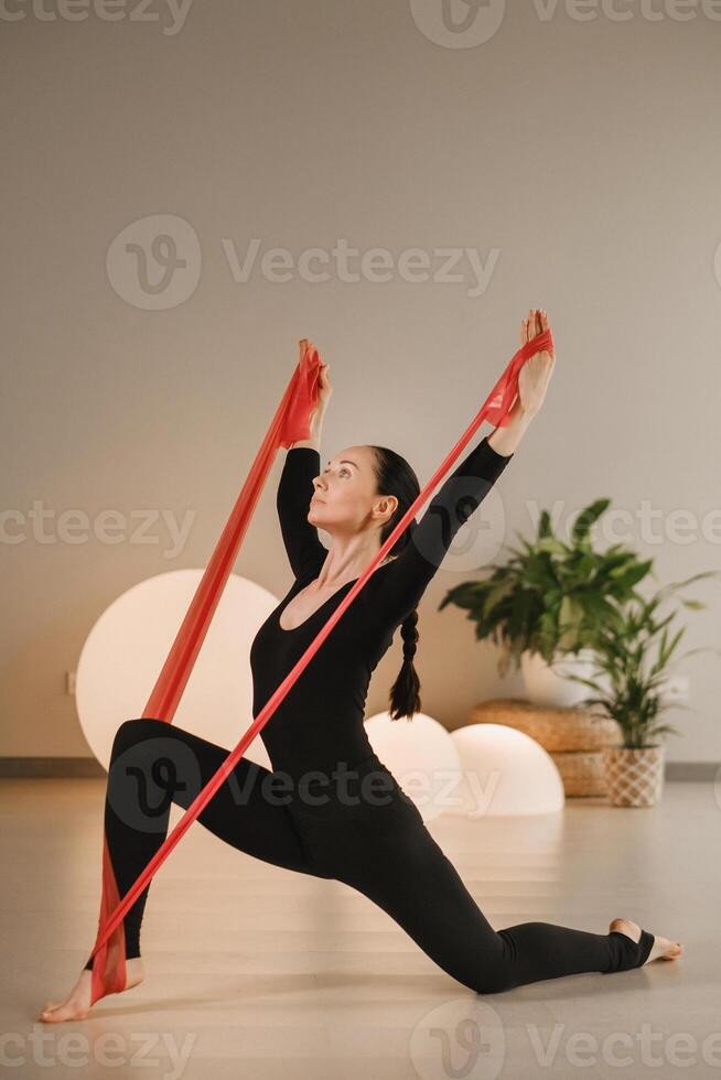 Girl in black doing fitness with red ribbons indoors photo