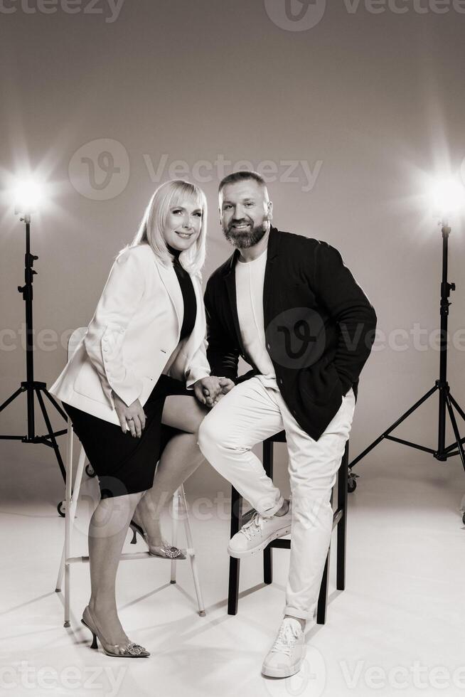 A man and a woman in strict clothes pose against the background in the studio photo