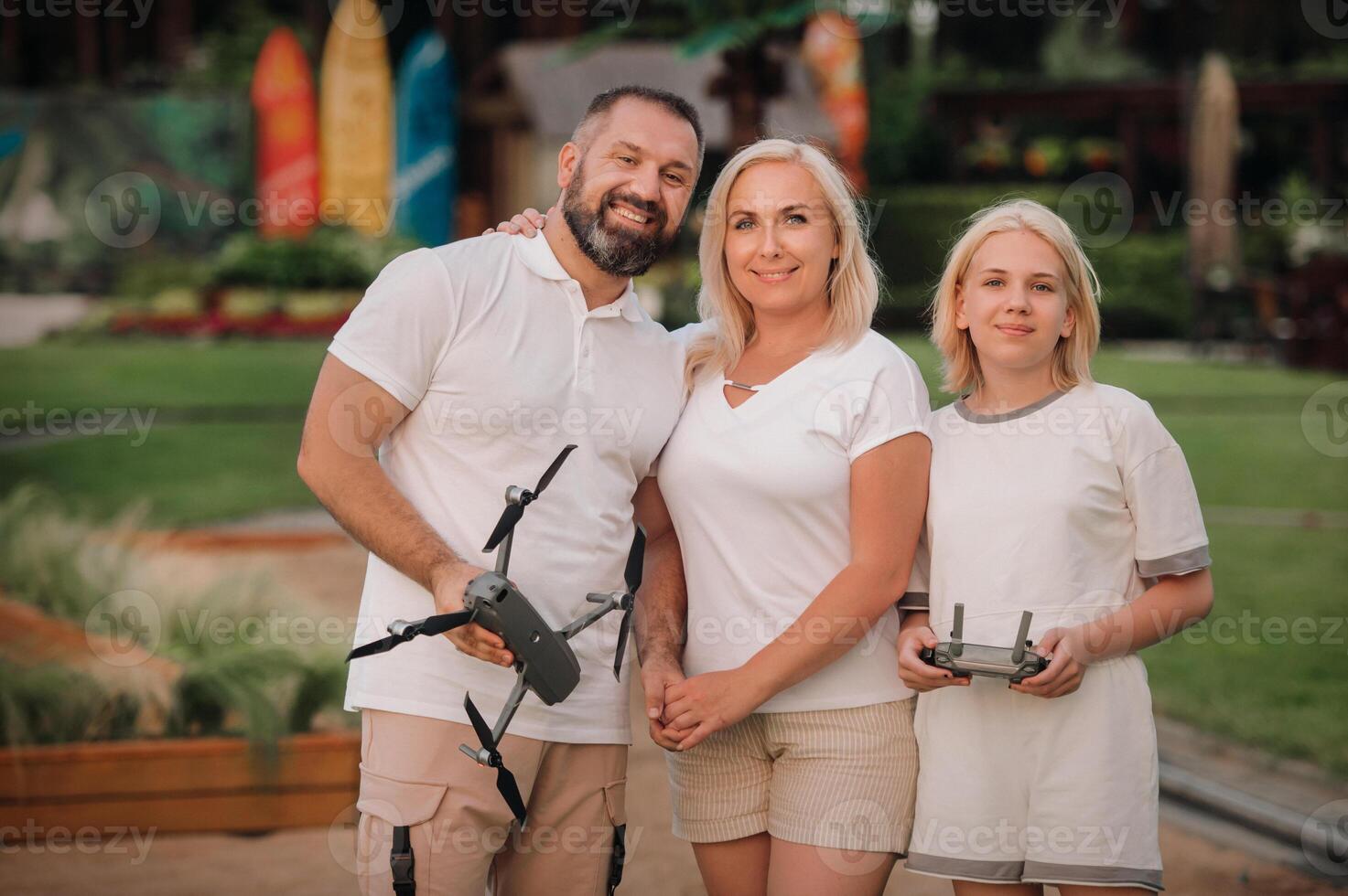The family is hugging and holding a quadcopter and a remote control in their hands photo