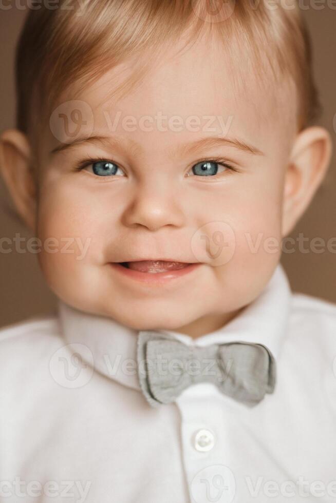 Portrait of a cheerful little boy in a white shirt with a bow tie photo