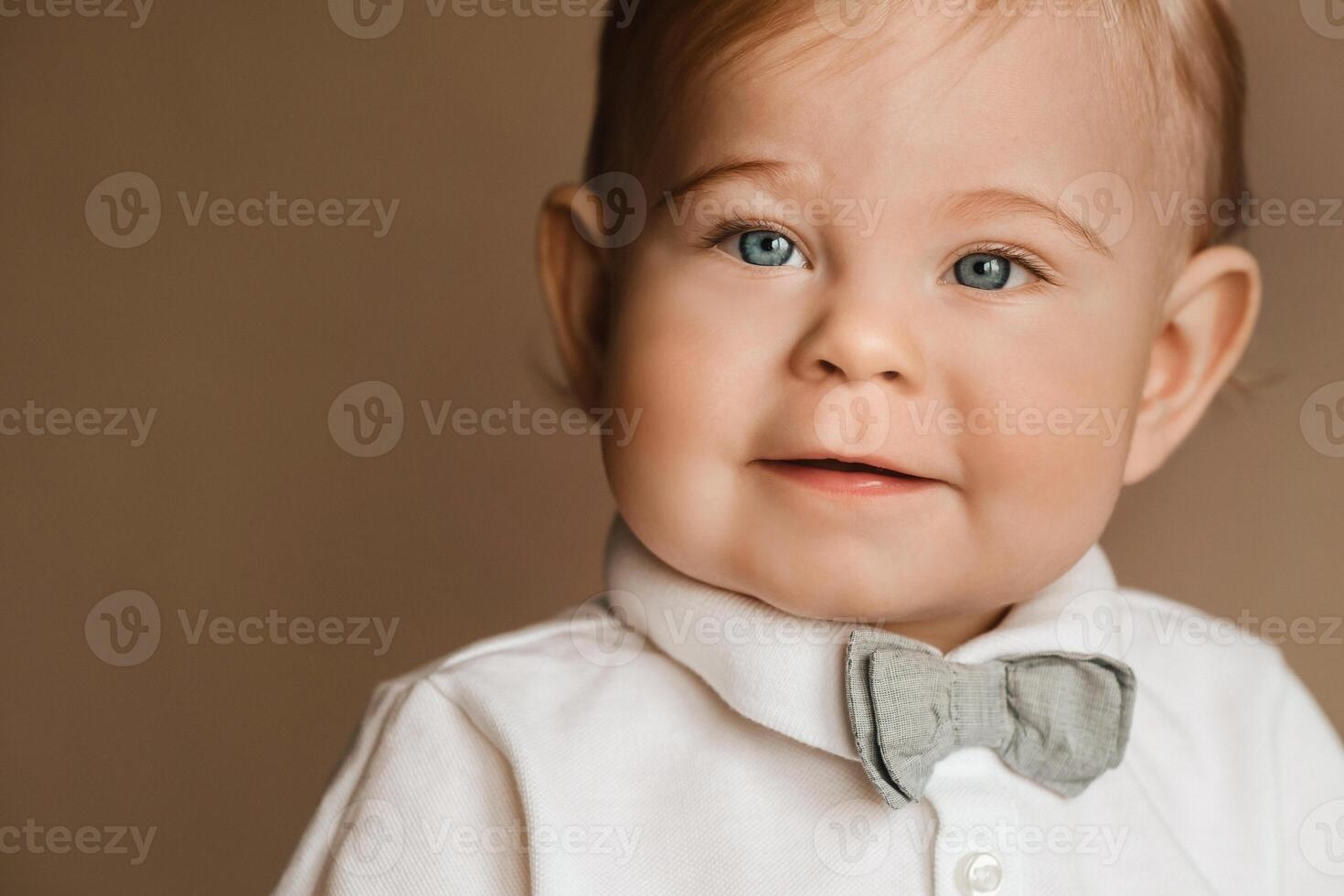 Portrait of a cheerful little boy in a white shirt with a bow tie photo