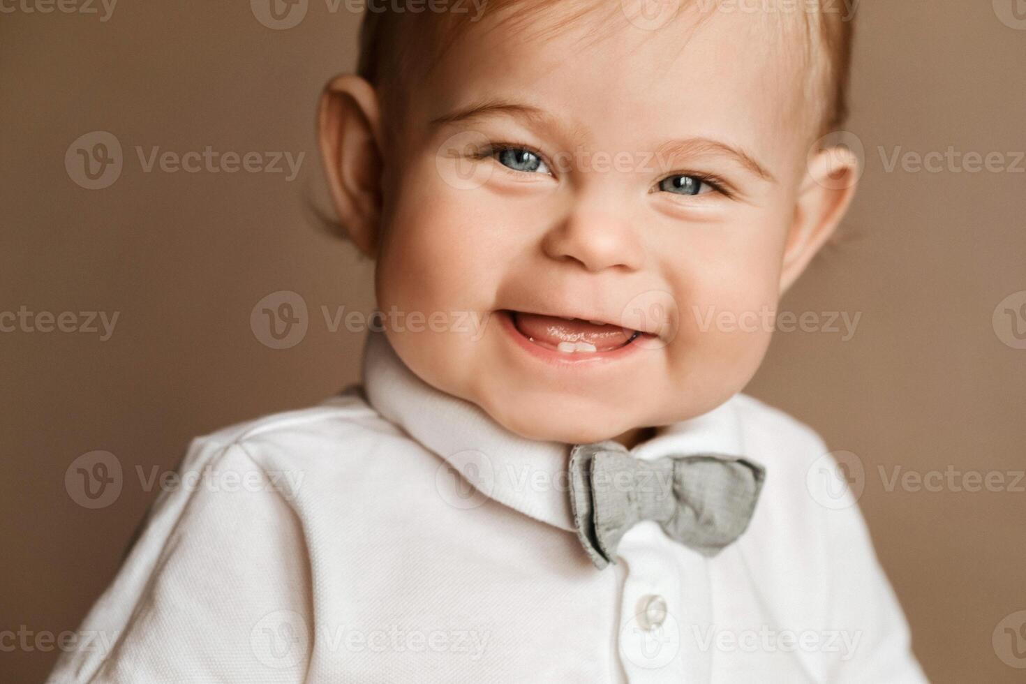 Portrait of a cheerful little boy in a white shirt with a bow tie photo