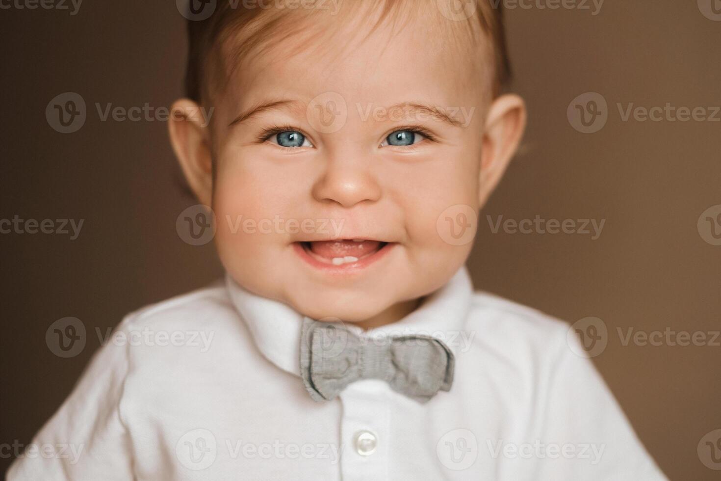 Portrait of a cheerful little boy in a white shirt with a bow tie photo