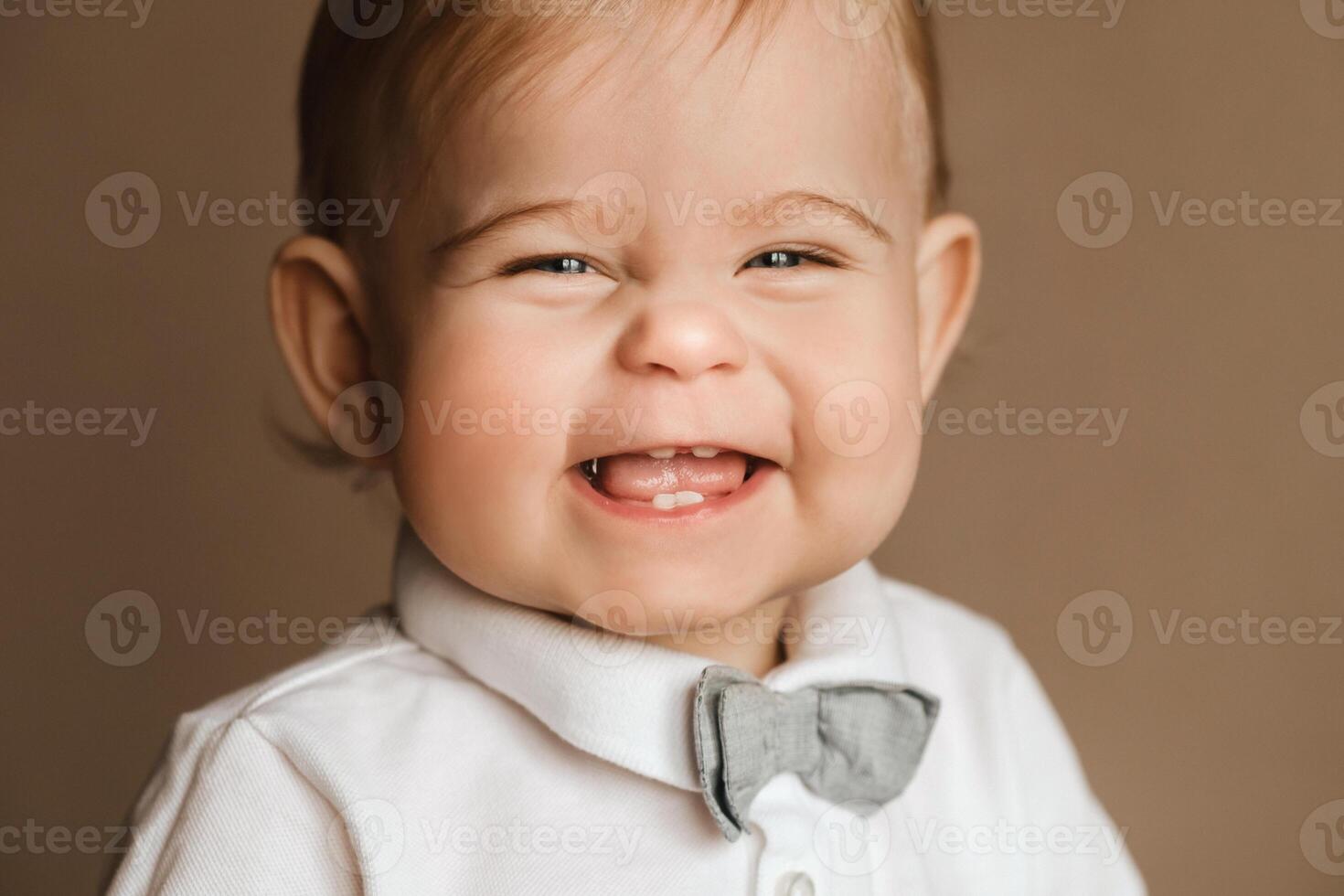 Portrait of a cheerful little boy in a white shirt with a bow tie photo