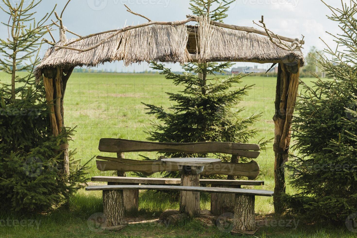 An old wooden gazebo for relaxing in the park. Equipped with wooden tables and benches photo