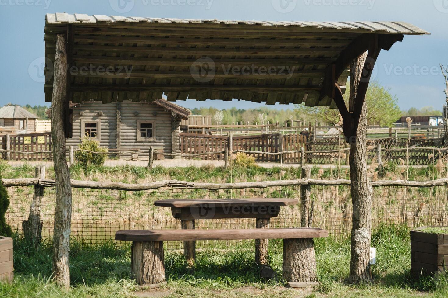 An old wooden gazebo for relaxing in the park. Equipped with wooden tables and benches photo