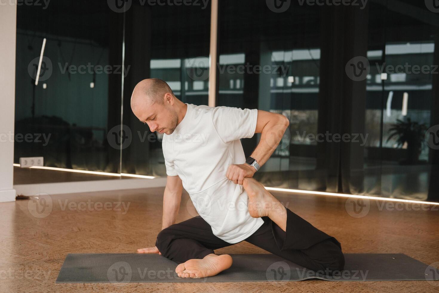 An athletic young man does exercises in the fitness room. A professional guy does yoga in the gym photo