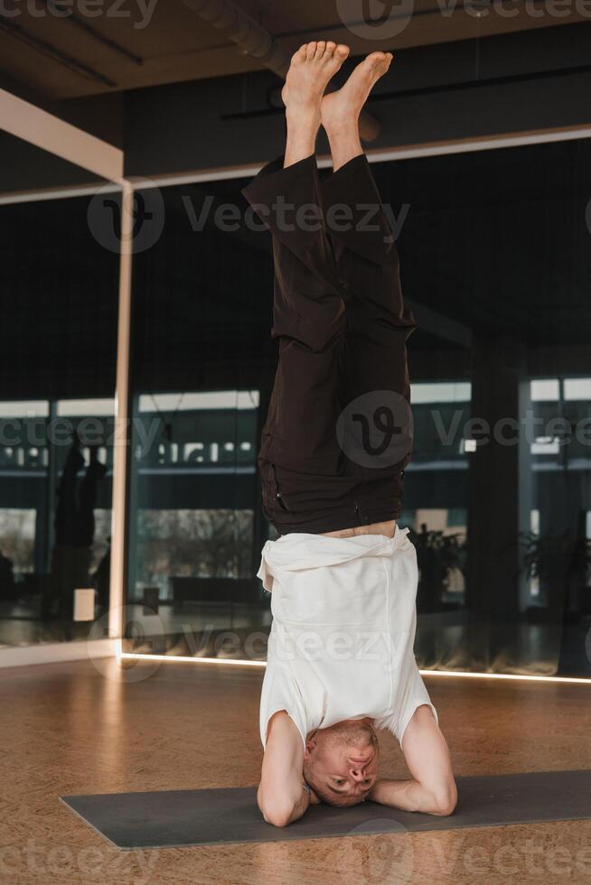 An athletic young man does exercises in the fitness room. A professional guy does yoga in the gym photo