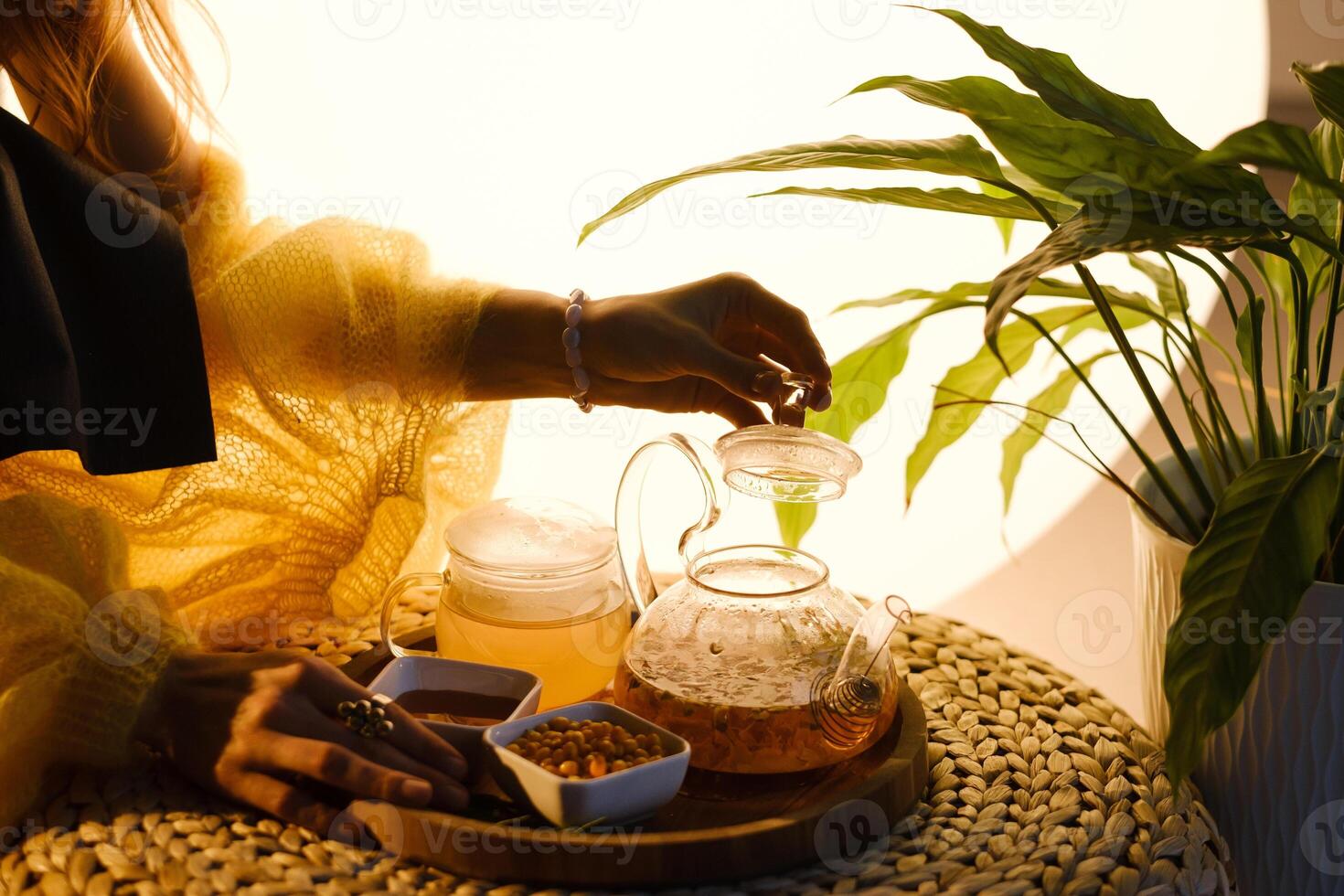 A teapot with sea buckthorn tea, honey and a plate with sea buckthorn on a tray photo