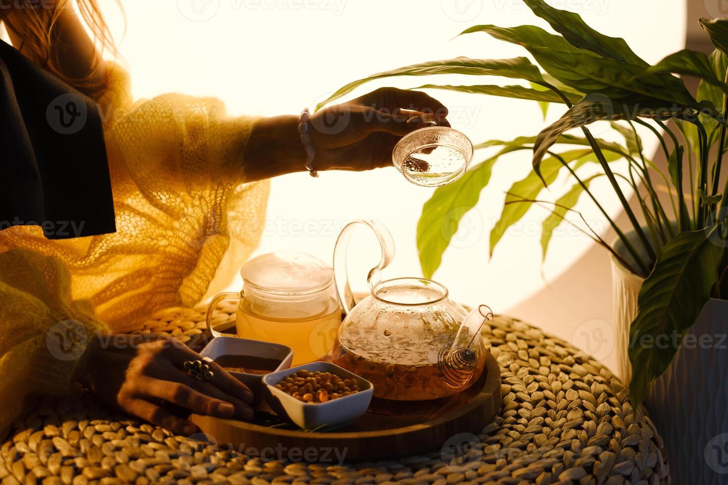 A teapot with sea buckthorn tea, honey and a plate with sea buckthorn on a tray photo