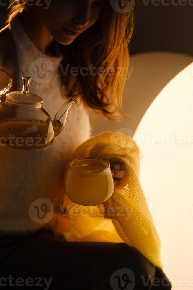 A young girl conducts an evening tea drinking procedure indoors. Relaxing tea party photo