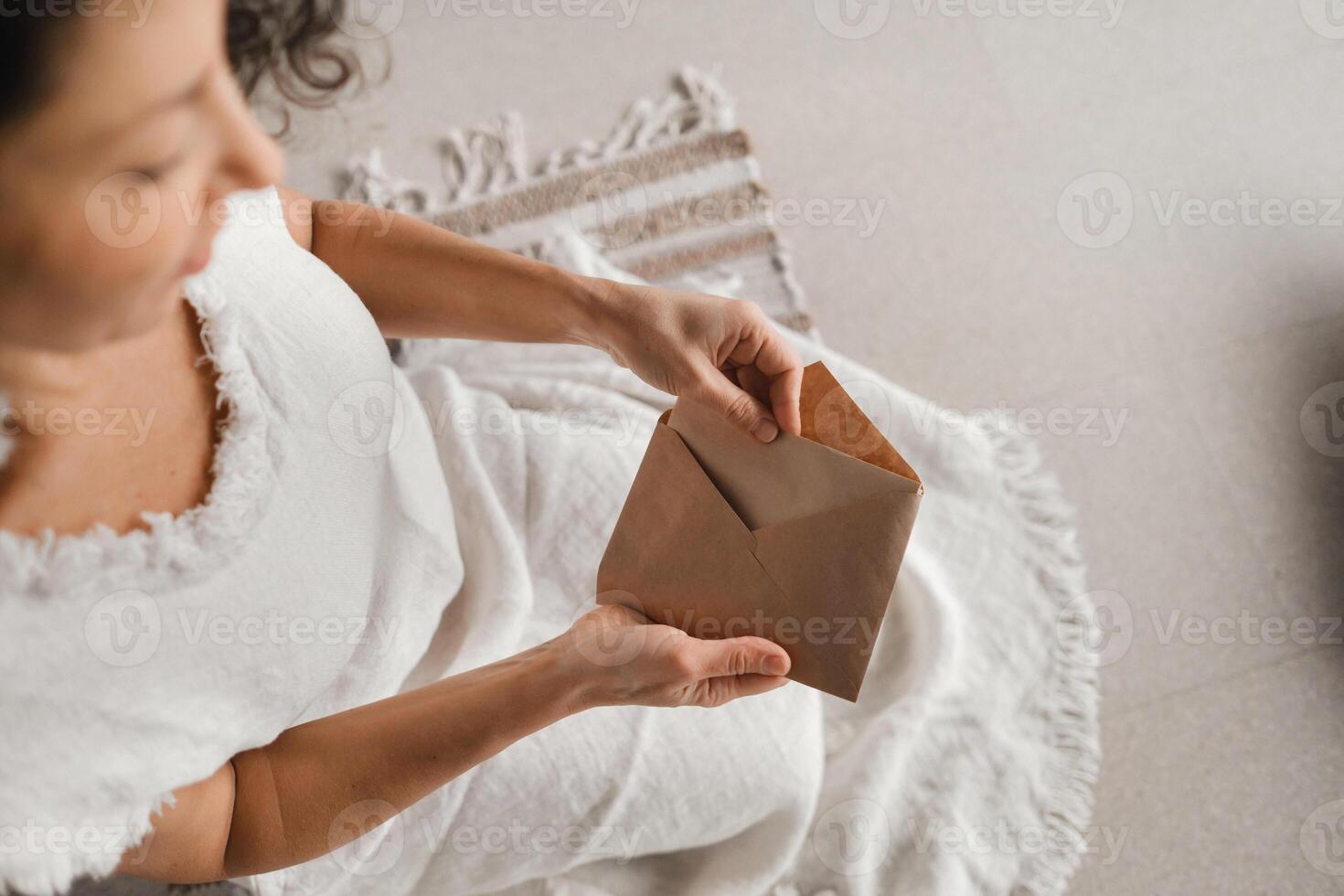 A woman in white clothes holds an envelope with a wish in her hands. The concept of a women's circle photo