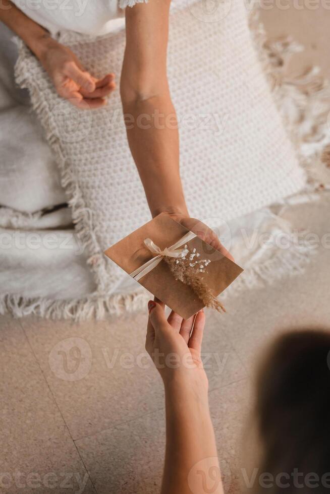 A woman in white clothes passes an envelope with a wish to another woman. The concept of the women's circle photo
