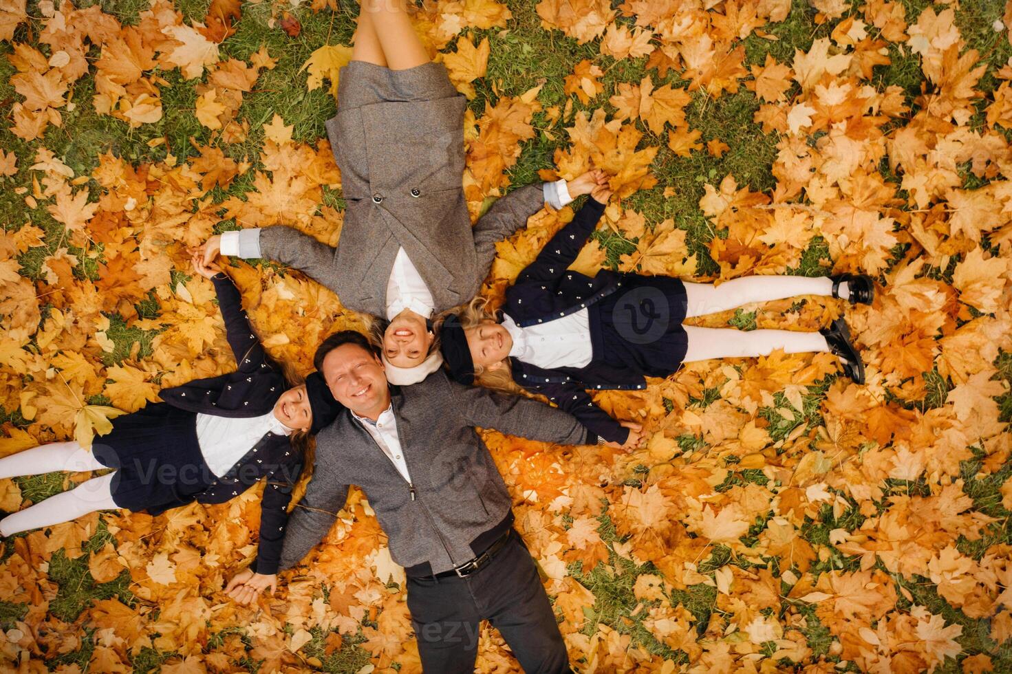 A large family holding hands are lying in an autumn park .Happy people in the autumn park photo