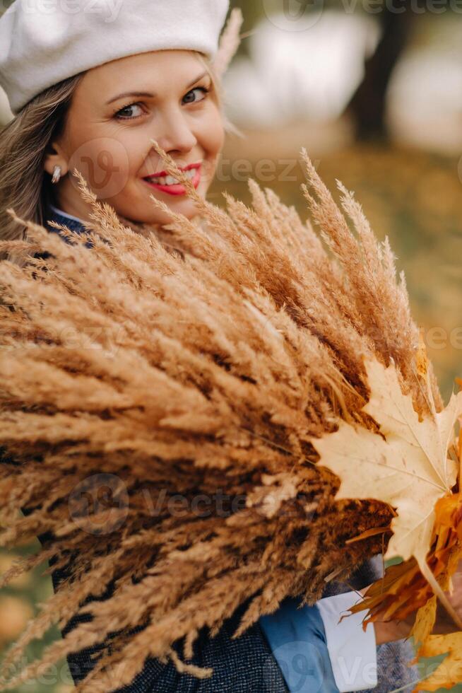 Portrait of a Girl in a jacket and birette with an autumn bouquet in an autumn park photo