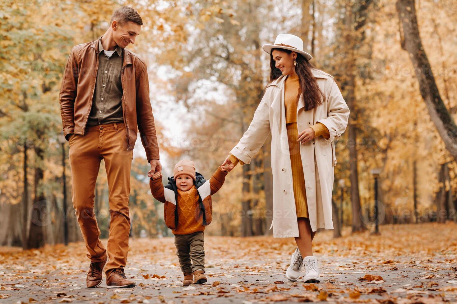 Father and mother with son walking in the autumn Park. A family walks in the Golden autumn in a nature Park. photo