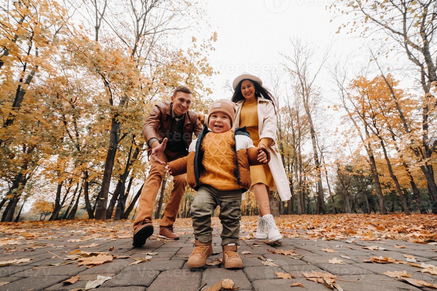 Father and mother with son walking in the autumn Park. A family walks in the Golden autumn in a nature Park. photo